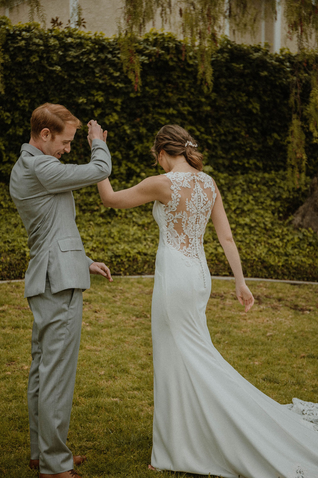 the bride twirls around her groom in her lace wedding dress