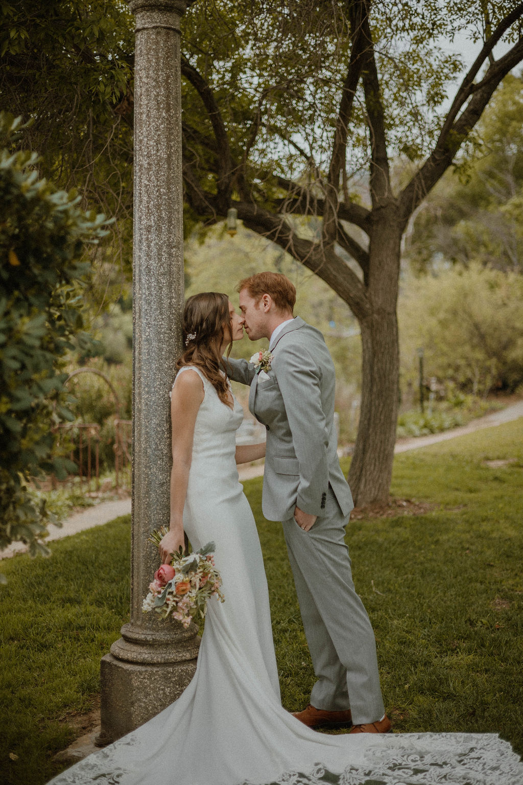the groom leaning in for a kiss by the lamp post at the California wedding venue