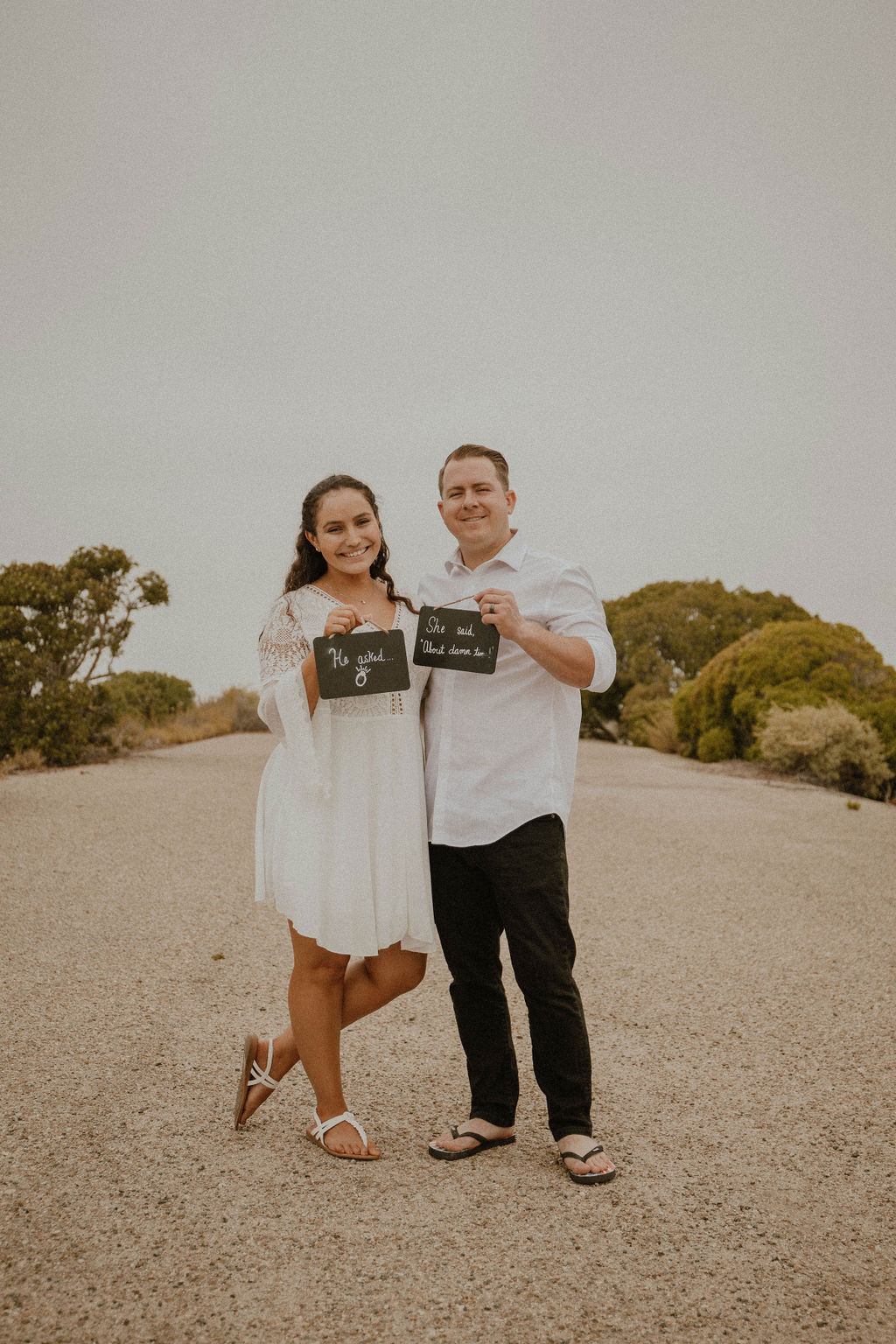 couple holding signs at their engagement shoot at Point Mugu Naval Base