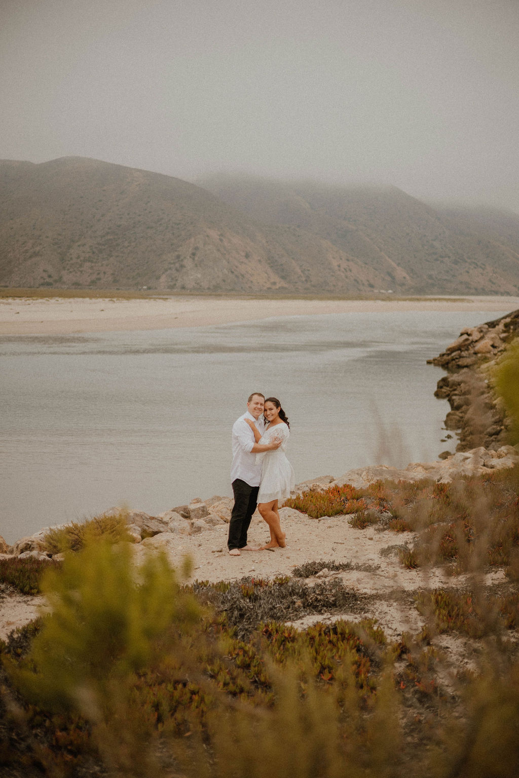couple grinning at the camera for their engagement photoshoot at Point Mugu Naval Base
