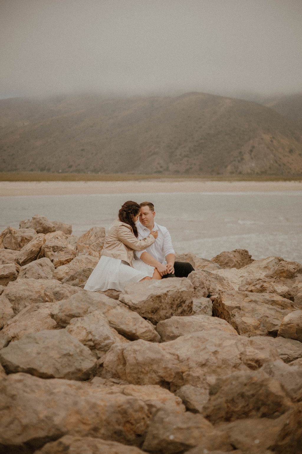 she caresses his face as they sit near the beach at Point Mugu Naval Base