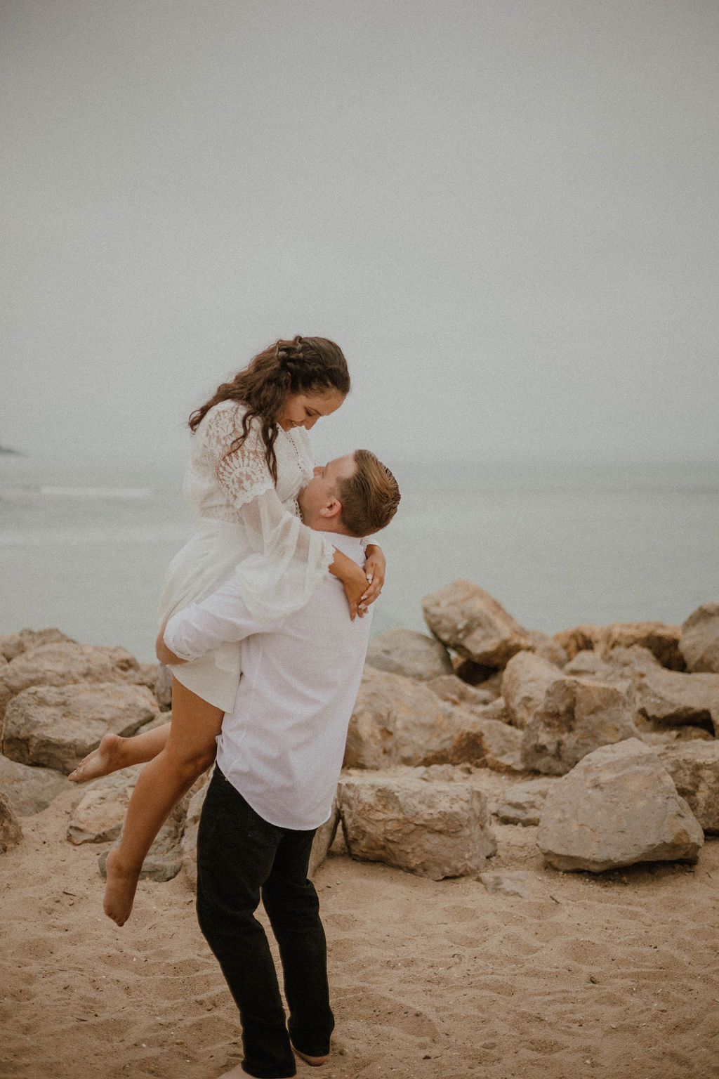 Fiance holding her up for a cute pose for their engagement session