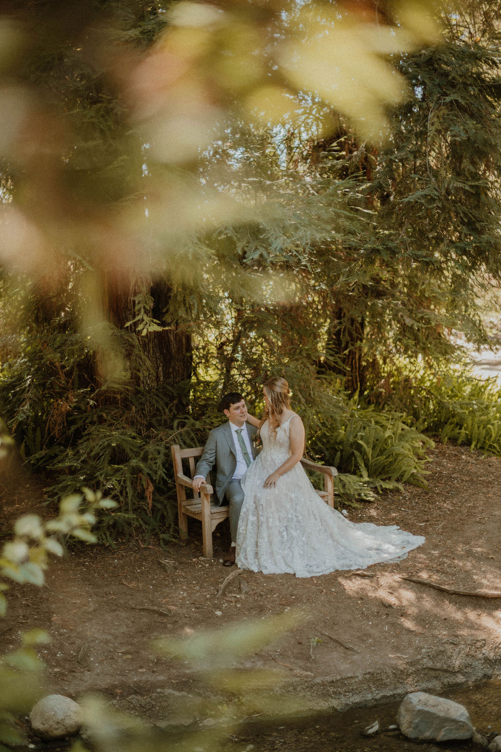 the couple sitting on a park bench during their Fullerton Arboretum Wedding