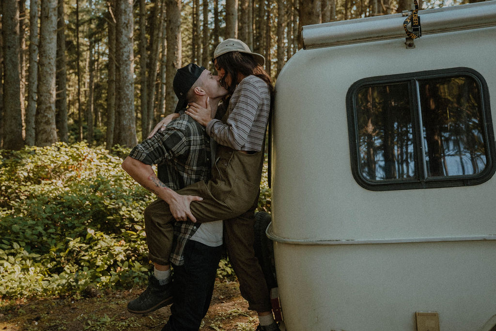 the couple kissing behind their camper at their camp photoshoot