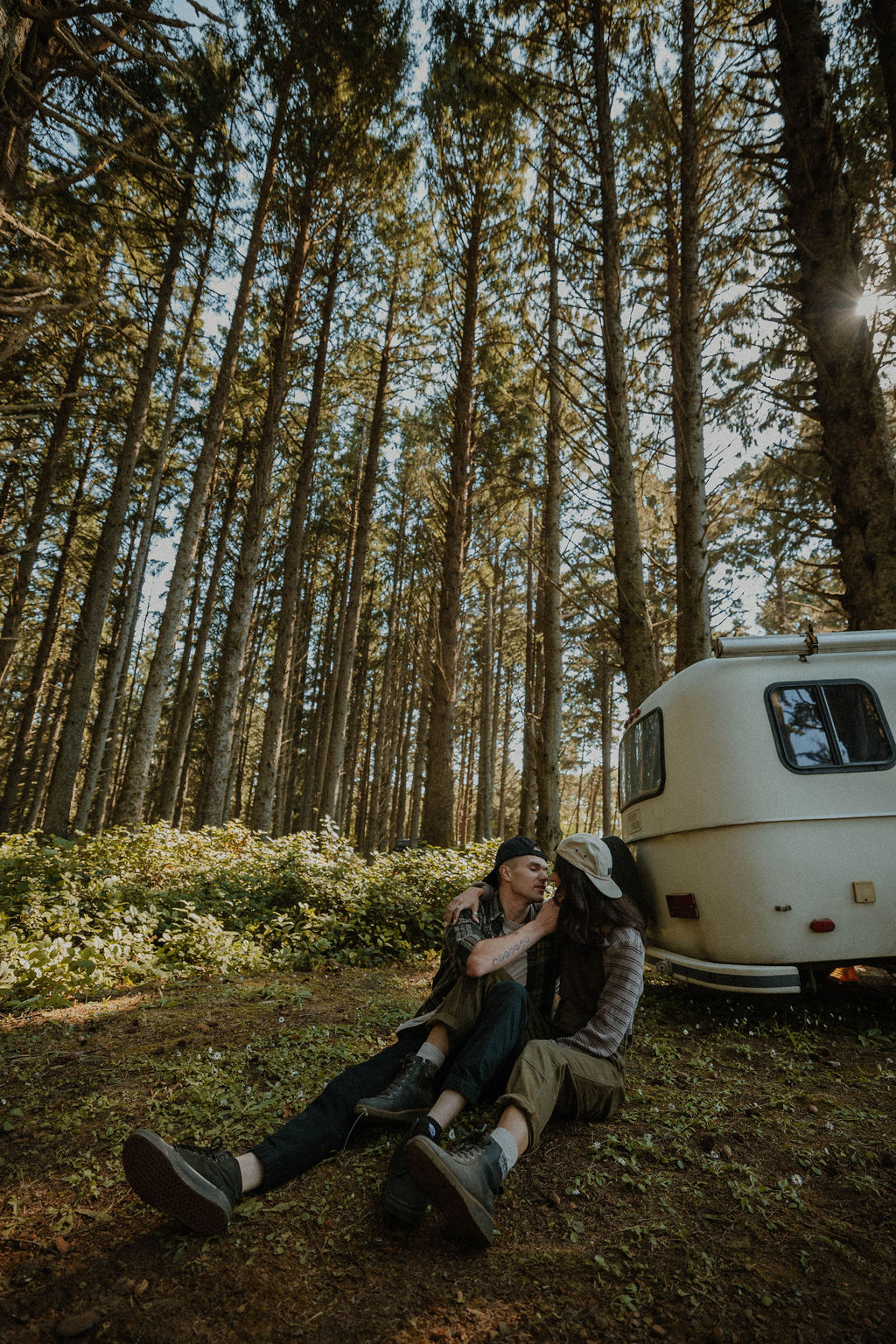 the couple sitting in the forest next to their camper