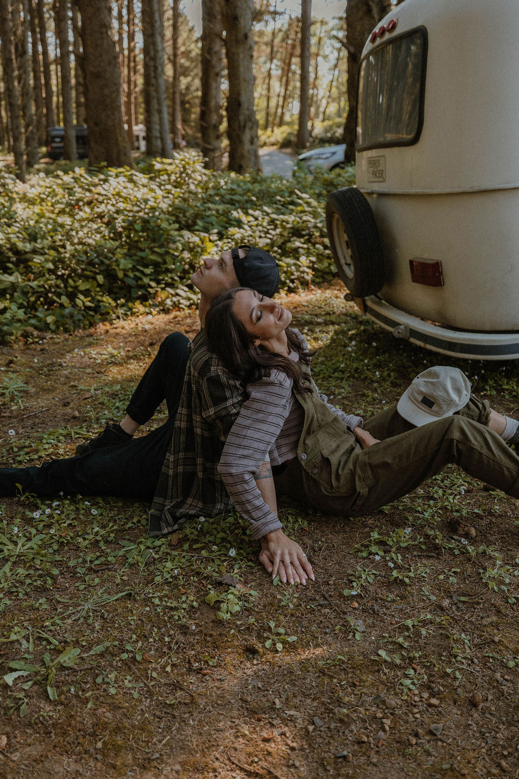 the couple sitting back to back on the ground at their camp photoshoot