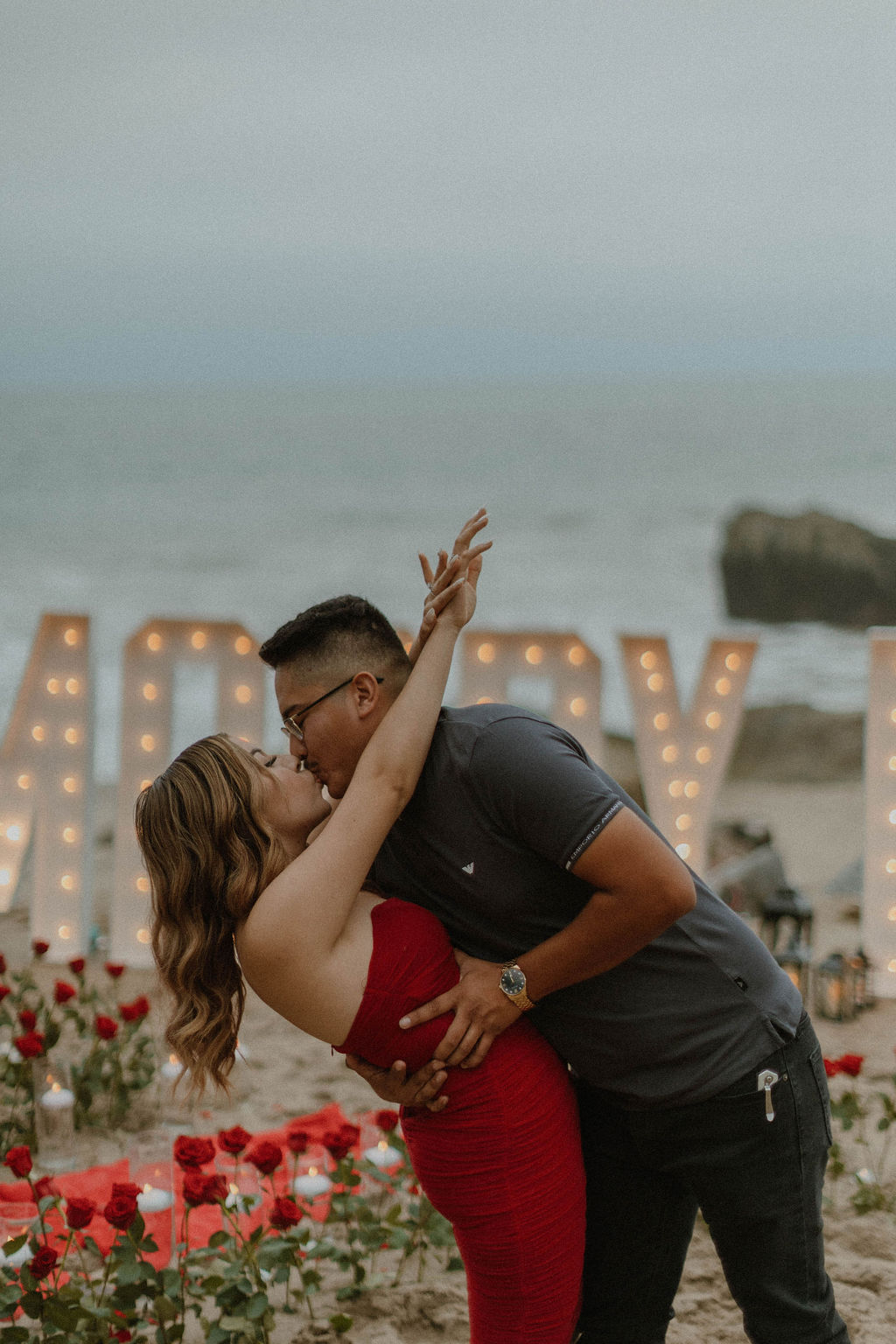 the couple kissing after their proposal on the beach