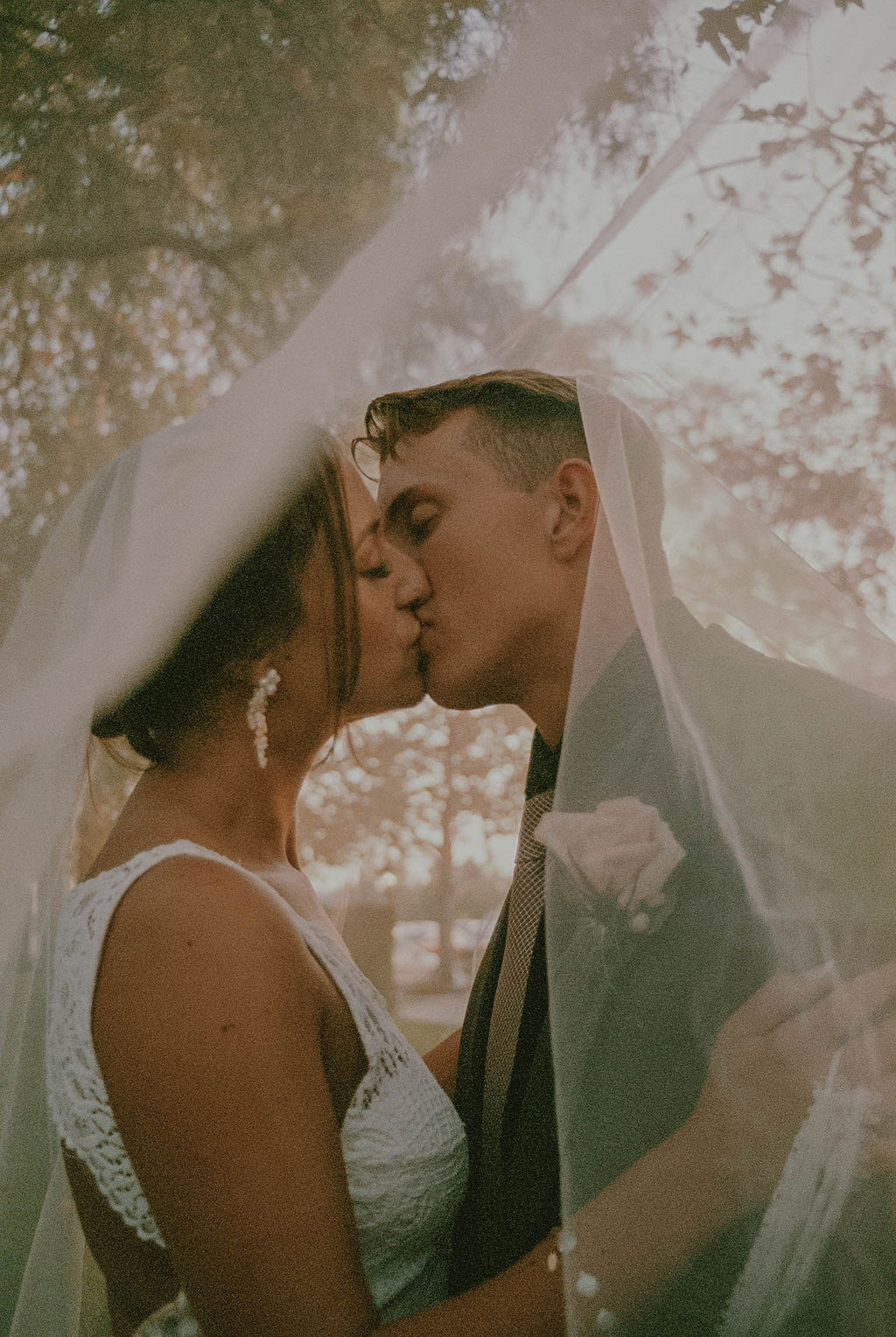 the couple kissing underneath the wedding veil